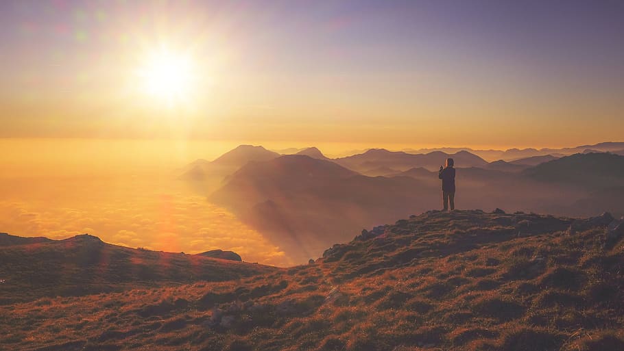 man standing on montain looking at sunset